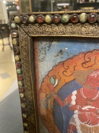 A Tibetan thangka in inlaid gilt brass frame, 19th C.